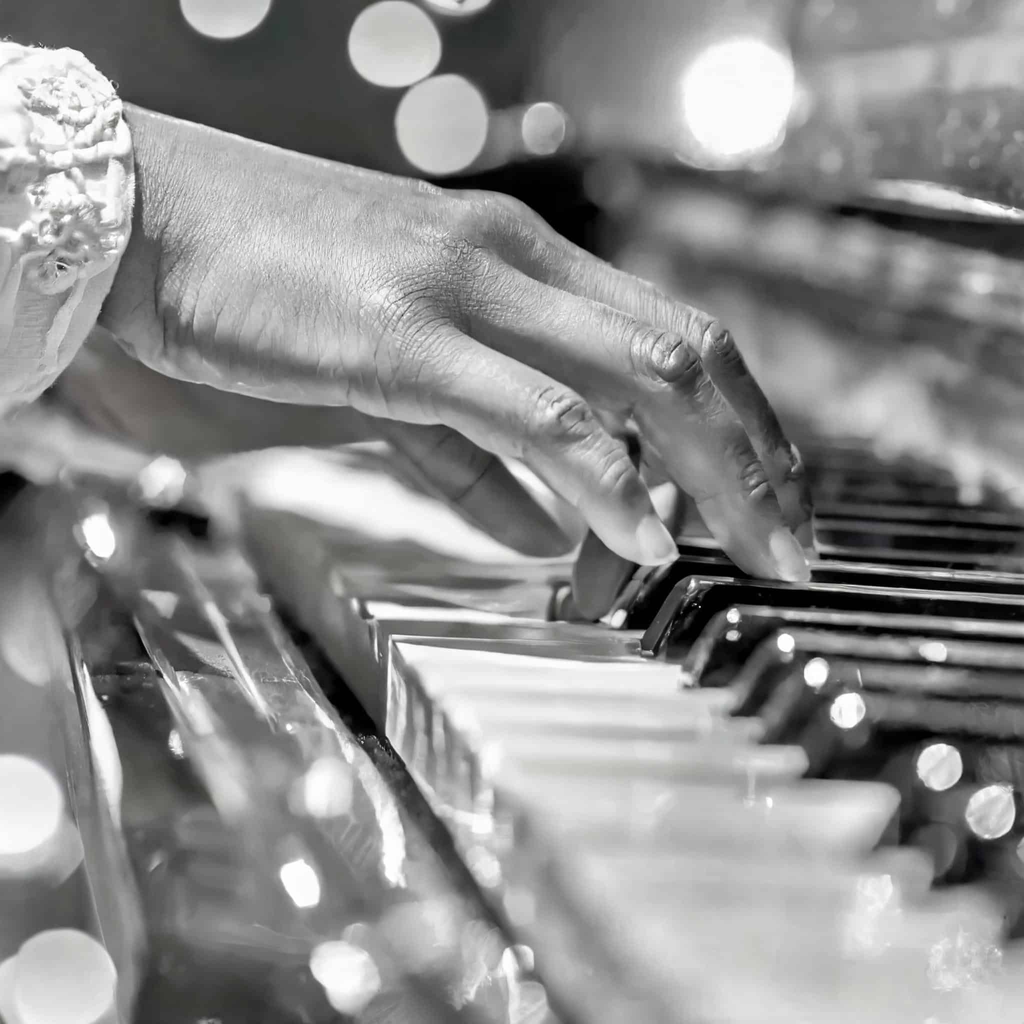 A black and white extreme close-up of hands gracefully playing a scale on the piano keys, showcasing musical talent and skill.