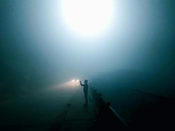 a person standing outdoors in fog