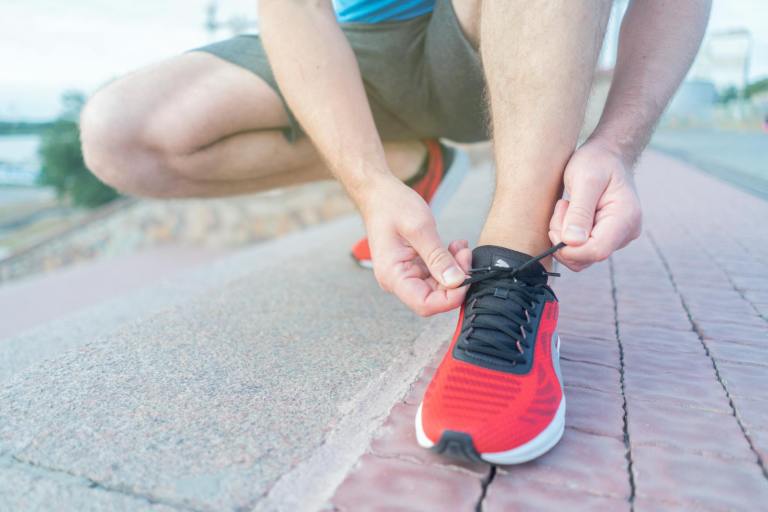 close up shot of person tying his red sneakers