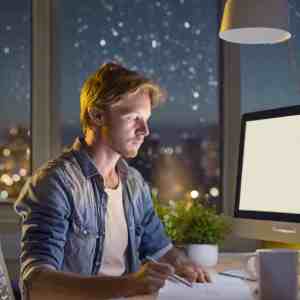 Writer contemplating under the night sky with a blank screen, seeking inspiration.