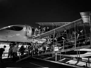 Travelers ascending airplane stairs under dawn light, inspiring poetry.
