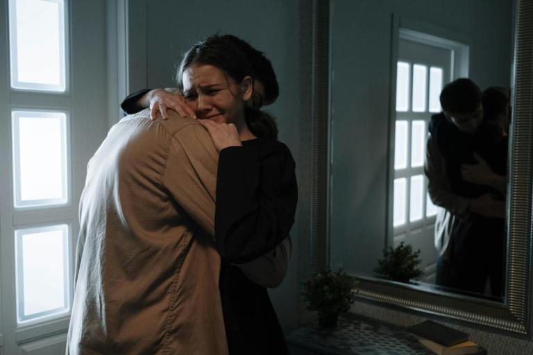 an emotional woman crying while hugging another person