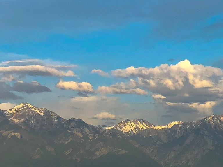 Snowpacked peaks of the Wasatch Mountains on a scattered cloudy day.