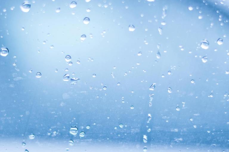 close up of water droplets against blue background